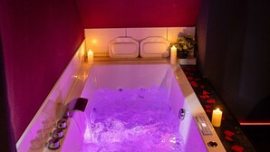 Eine Wellnessbadewanne mit Eis, Kerzen und Rosenblättern.
