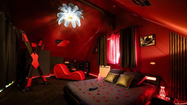 Ein Schlafzimmer mit einem großen Bett, roten Wänden und einer einzigartigen Deckenleuchte.