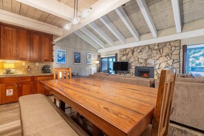Un vaste espace de vie comprenant une grande table à manger en bois, une cheminée en pierre et un mur en pierre.