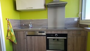 A kitchen with a dishwasher, oven, and a stainless steel range hood. - TOWN CENTER QUIBERON (Quiberon)
