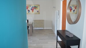 A hallway with a wooden dresser, a black console table with a basket, and a world map painting on the wall. - TOWN CENTER QUIBERON (Quiberon)
