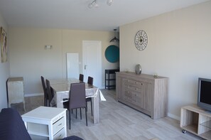 Un salon moderne comprenant un coin repas, un meuble pour la télévision et une horloge murale.