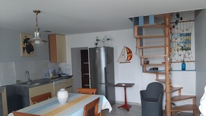 A modern kitchen with a dining area, a refrigerator, a wooden table, and a red chair. - Little corner of paradise 2 steps from the sea. Walled garden. Wireless (Loctudy)