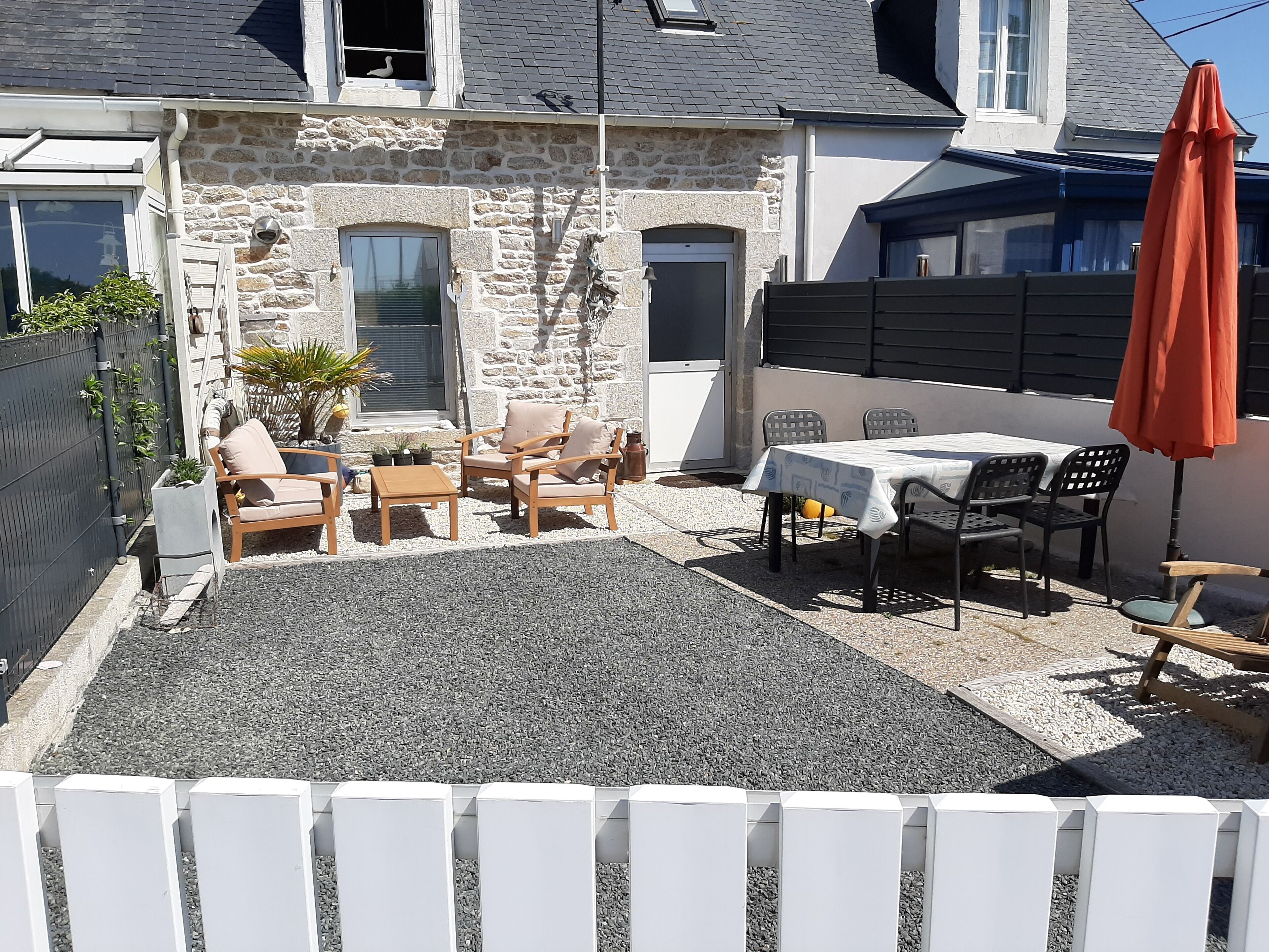 Une maison en pierre dotée d’un patio aménagé avec du mobilier d’extérieur et une table.