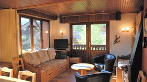 Un salon chaleureux avec un plafond en bois, un canapé, un téléviseur et une table à manger.