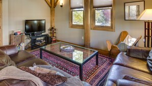 A cozy living room with a glass coffee table, leather sofas, a television, and wooden beams on the ceiling. - Downtown Durango-New Custom Timber Frame-the Carriage House (Durango)