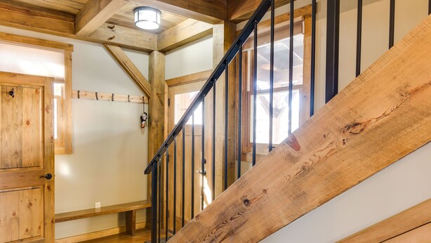A wooden staircase with a metal handrail, a wooden door, and a light fixture on the ceiling. - Downtown Durango-New Custom Timber Frame-the Carriage House (Durango)