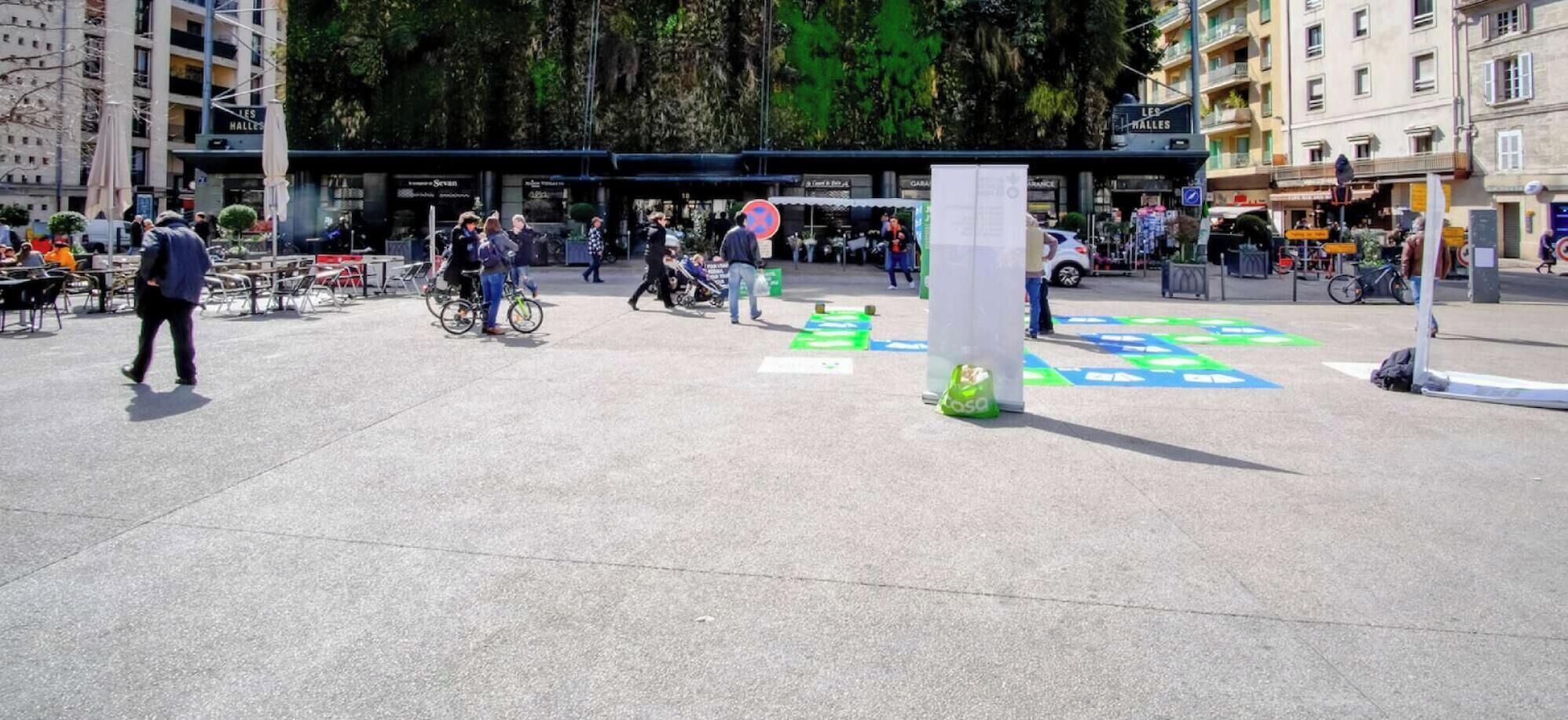 A pedestrian area with outdoor seating and a large tree in the background.