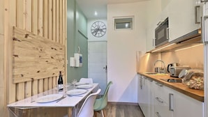 A compact kitchen with a wooden wall, a clock, and a small window.