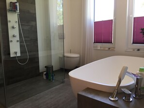 Een bad/douchecombinatie, een haardroger, handdoeken, toiletpapier