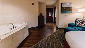 A hotel room with a large bathtub, a bed, a desk, and a chair. - Portlander Inn and Marketplace (Portland)