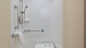 Um chuveiro pequeno e fechado, com parede revestida de azulejos brancos, chuveiro fixo, chuveiro manual, porta-toalhas e um pequeno armário.