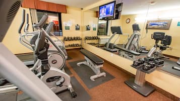 Ein Fitnessraum mit Laufbändern, Hanteln und einer Trainingsbank.