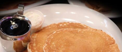 Une assiette de crêpes et une petite tasse de sirop.