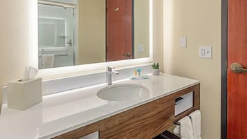 A modern bathroom with a large mirror, dual sinks, wooden vanity, and a towel rack.