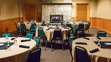 A conference room with round tables, chairs, and a stone fireplace.