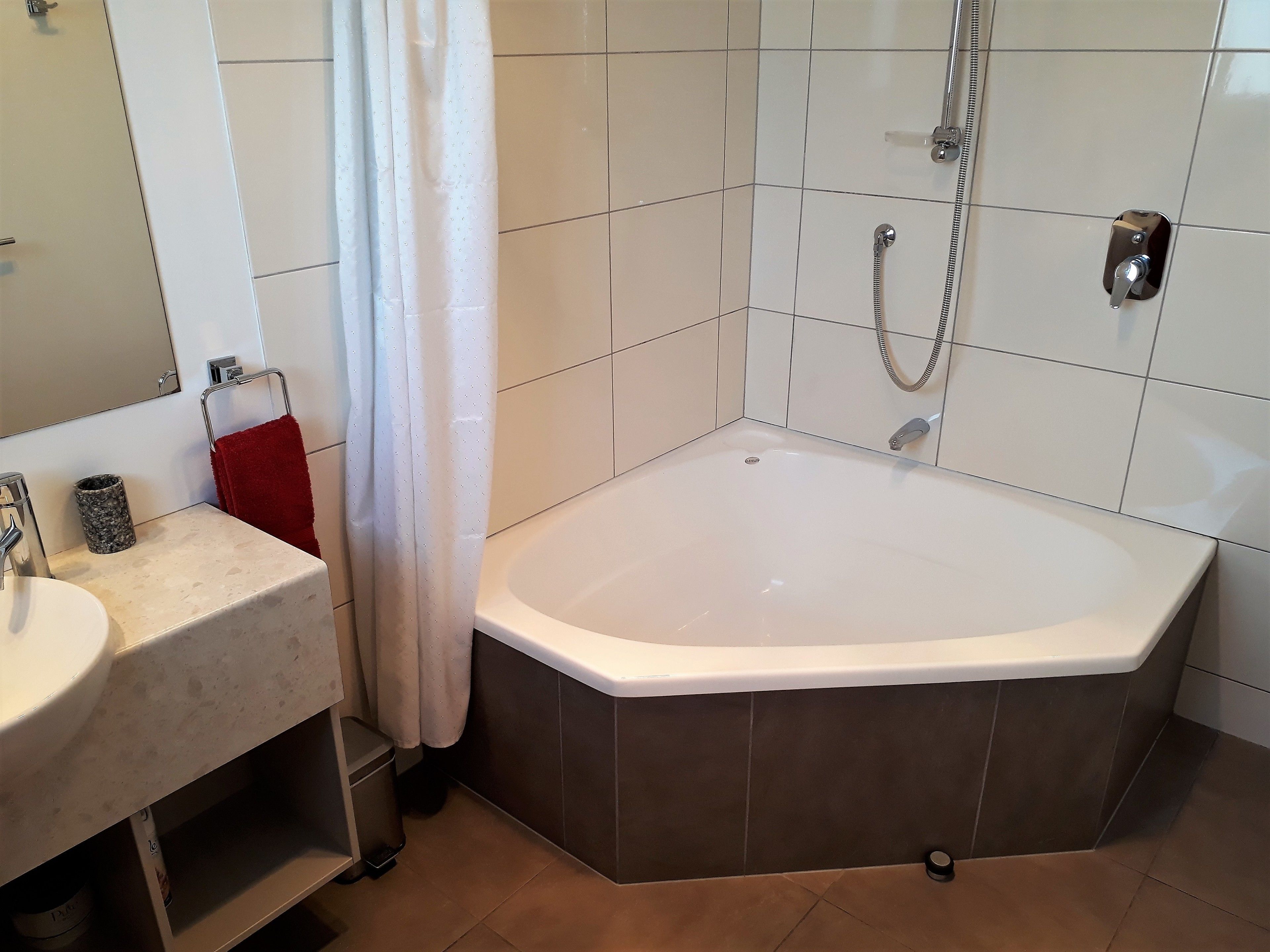 A bathroom with a bathtub, a sink, a mirror, and a shower.