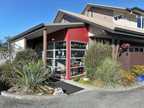 A modern building with a reception area, including a reception desk and a window with a sign. - Mohua Motels (Takaka)