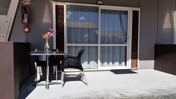 A modern building with a large sliding glass door, a small table with chairs, and a vase with flowers.