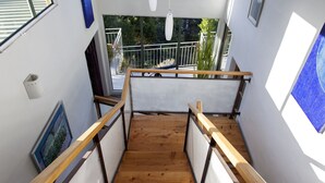 Una escalera de madera con vistas a un paisaje costero a través de amplios ventanales.