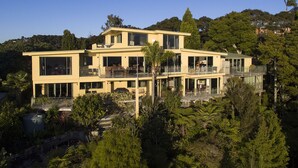 Una casa moderna de dos pisos con ventanas amplias, balcones y un jardín exuberante.