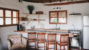 A kitchen with a central island, wooden chairs, a refrigerator, and a stove. - Casa Paz (Isla Holbox)