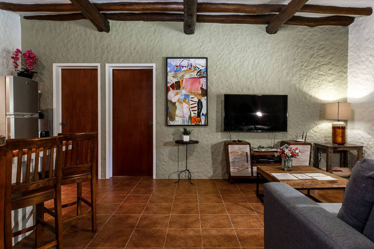 A living room with a TV, wooden furniture, a painting, and a lamp.
