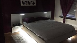 A bedroom with a bed, a nightstand, and two wall-mounted light fixtures. - Luxury apartment (Apach)
