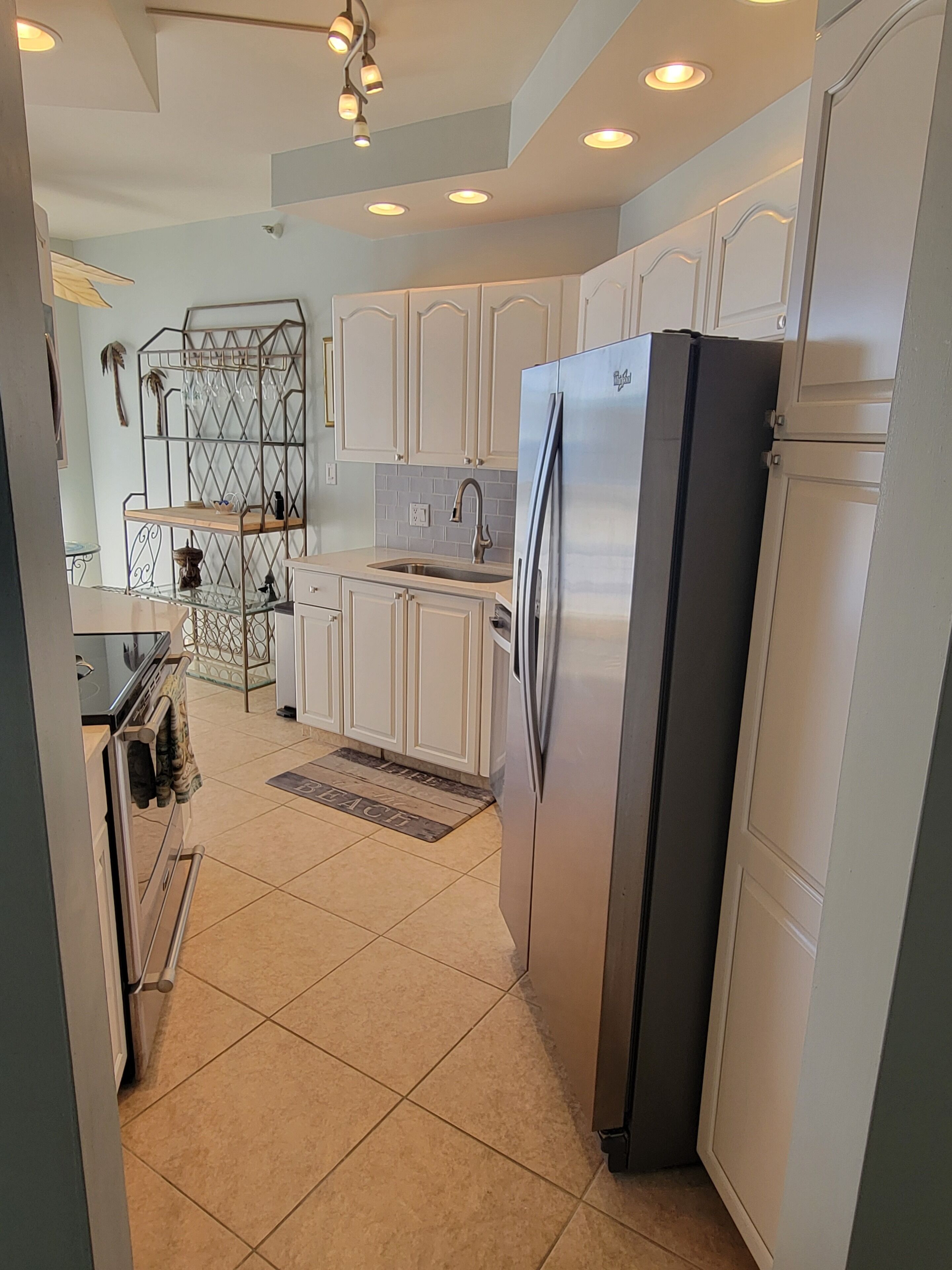A modern kitchen with white cabinets, a stainless steel refrigerator, and a built-in oven.