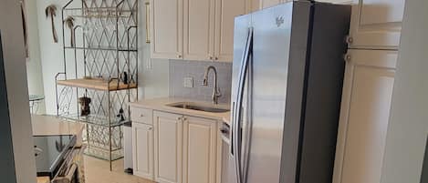 A modern kitchen with white cabinets, a stainless steel refrigerator, and a built-in oven.