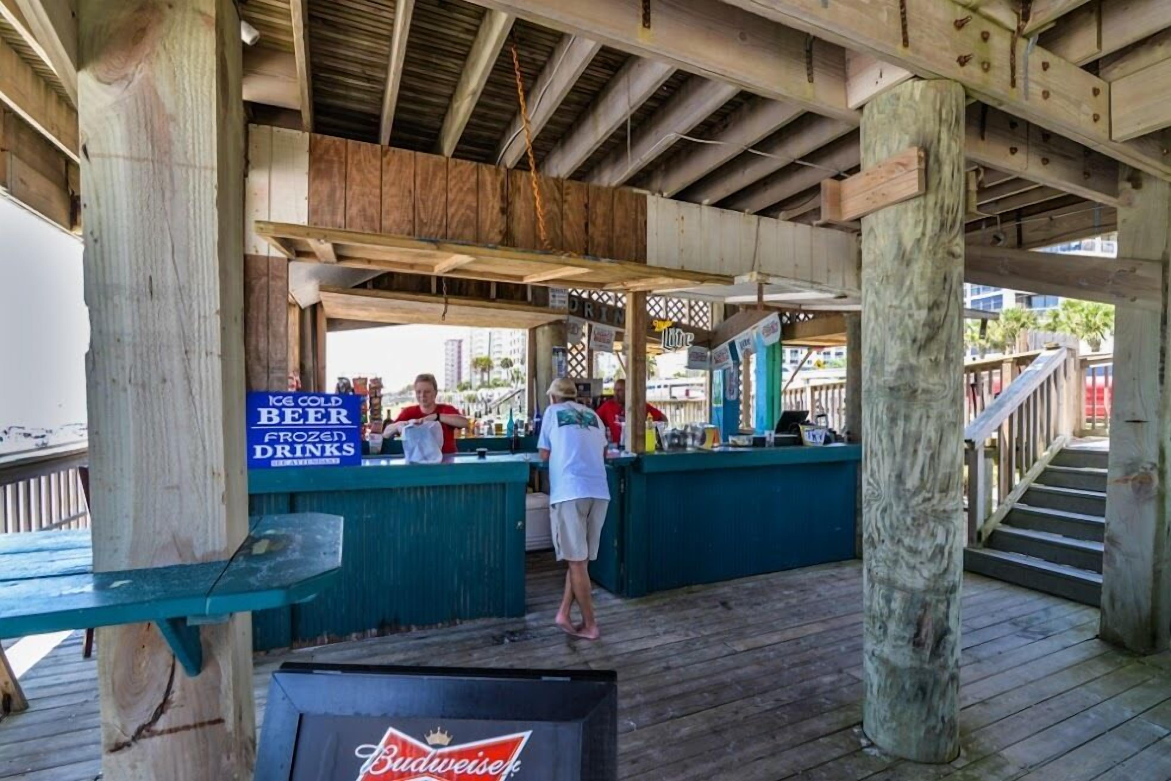 A wooden deck with a bar area offering beer and frozen drinks.