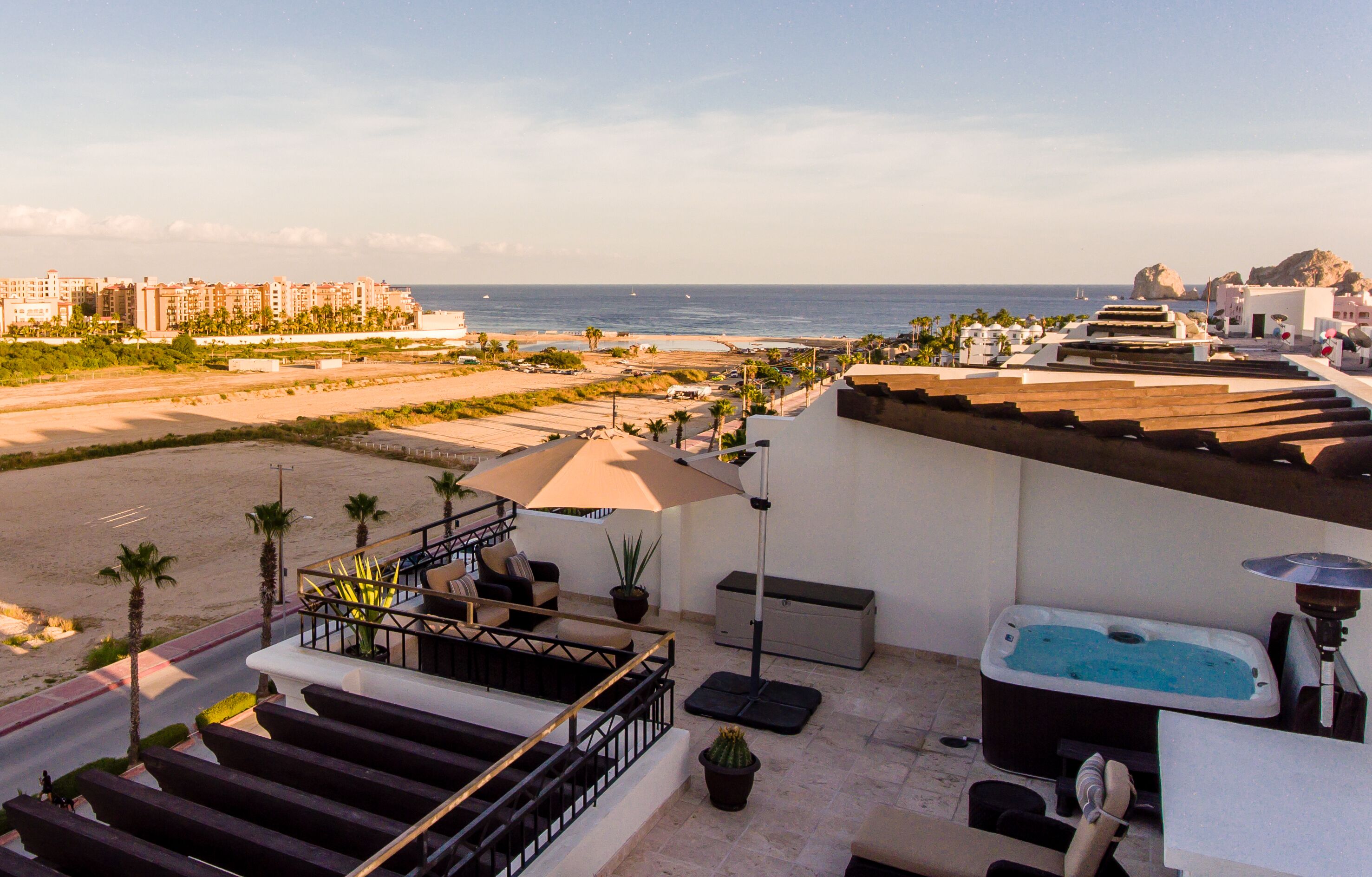 A rooftop terrace with a pool, outdoor seating, and a view of the beach and ocean.