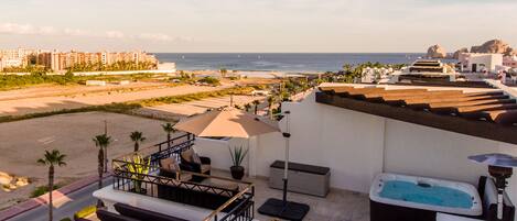 A rooftop terrace with a pool, outdoor seating, and a view of the beach and ocean.
