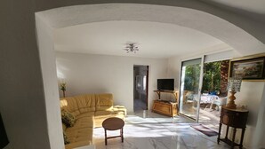 Una sala de estar con un sofá, una mesa de centro, un televisor sobre un mueble de madera y un cuadro en la pared.