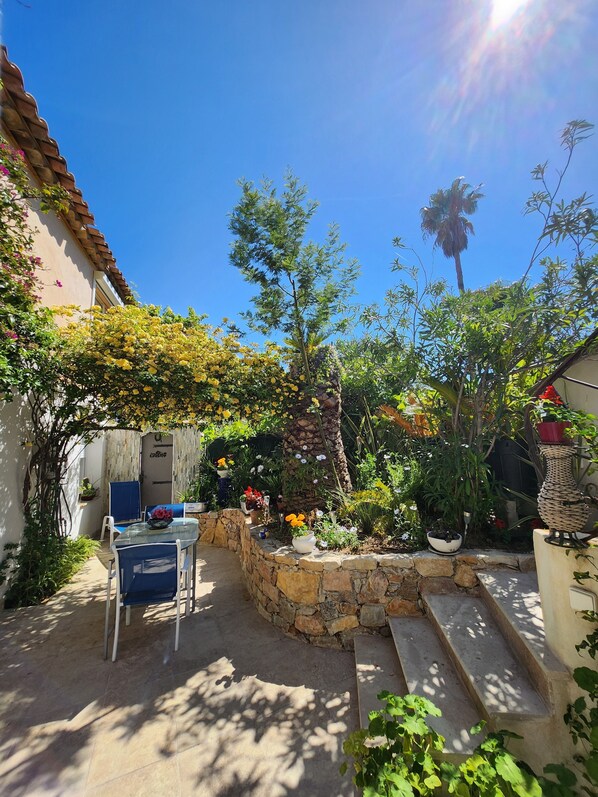 A patio with a stone wall, a table, and chairs.