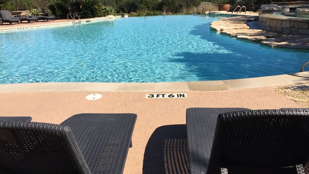 A swimming pool with lounge chairs and a view of the hills.