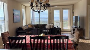 A dining area with a chandelier, a red tablecloth, and wooden flooring.