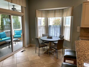 A dining area with a round table, chairs, and a view through a window with curtains. - Bayside * 4BR Fenwick Island Resort Vacation House (Selbyville)