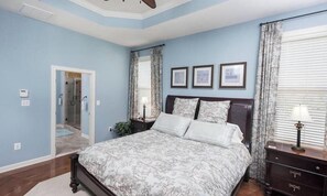 A bedroom with a bed, a nightstand, a lamp, a door, and a window with curtains. - Bayside * 4BR Fenwick Island Resort Vacation House (Selbyville)