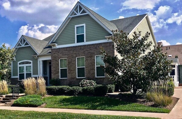 A two-story house with a brick facade, multiple windows, and a well-maintained lawn. - Bayside * 4BR Fenwick Island Resort Vacation House (Selbyville)