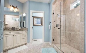 A bathroom with a shower, a sink with a mirror, and cabinets. - Bayside * 4BR Fenwick Island Resort Vacation House (Selbyville)