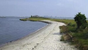 Un percorso costiero con spiaggia sabbiosa e zone erbose.