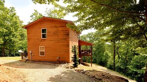 Une cabane en bois avec un porche, entourée d’arbres.