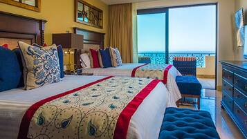 A hotel room with two beds, a balcony, and a view of the ocean.