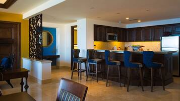 A modern kitchen with dark wooden cabinets, a central island with bar stools, and a blue accent wall.