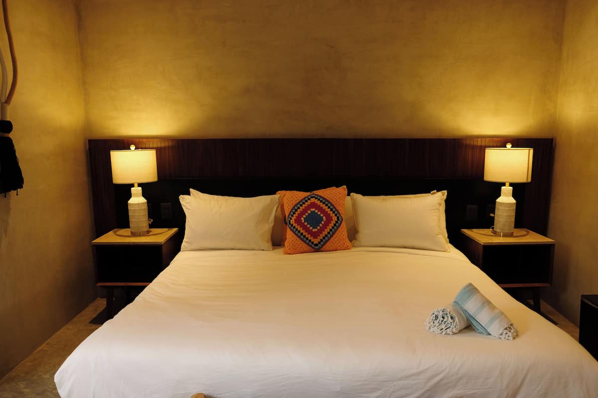 A neatly made bed with white linens, two bedside lamps, and a decorative pillow.