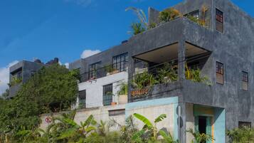 Un edificio moderno a più piani con balconi, ampie finestre e piante tropicali.