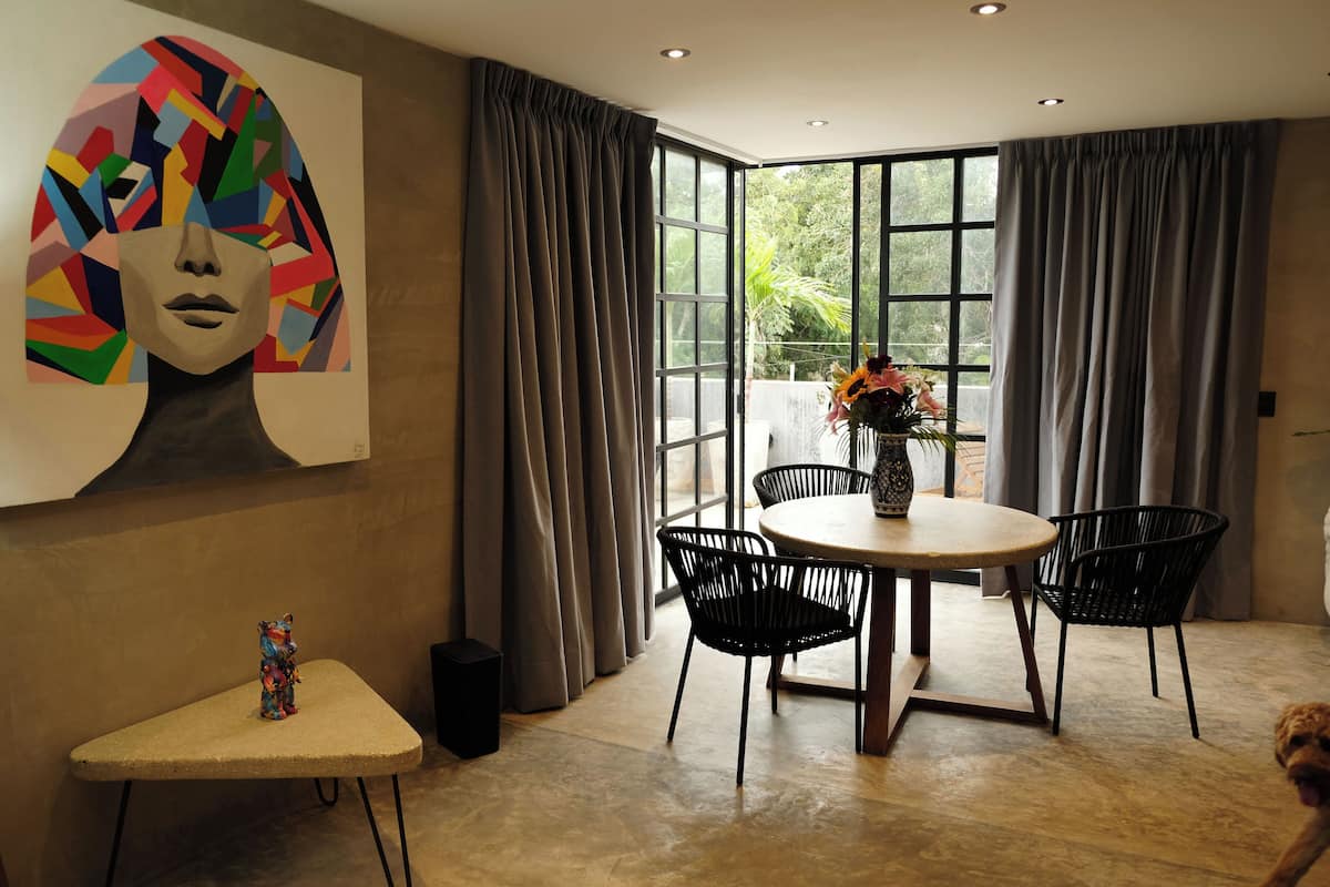 A modern dining area with a round table, black chairs, and a vase with flowers.