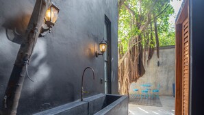 A modern bathroom with a black sink, two wall-mounted lights, and a wooden door.
