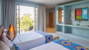 A bedroom with a large bed, a view of the outdoors, a wooden headboard, and a wall with shelves.